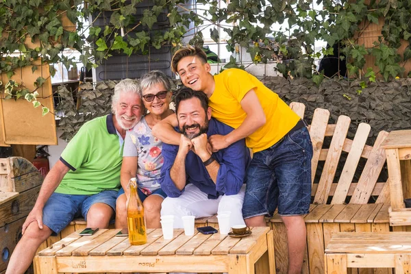 four different mixed generations grandfather father son all together in leisure activity. mobile phones on the table to represent technology and family concept connected to the modern world. colored clothes and happiness scene