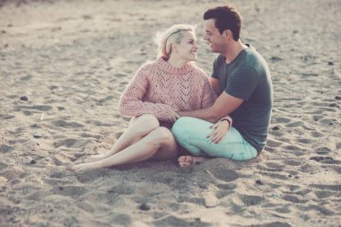 güzel model çift beyaz genç bayan ve erkek sarılma ve sahilde oturmuş aşk konaklayın. sarı ve siyah saç ilişki açık boş zaman etkinliği