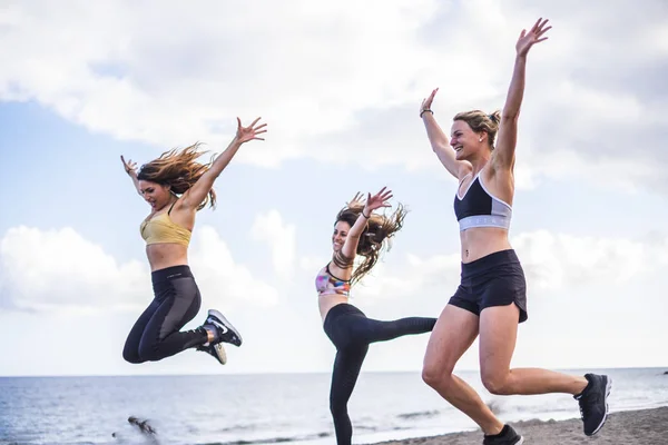 Üç güzel beyaz kız sahilde fitness egzersiz yapıyor atlama. açık eğlence spor aktivitesi için birlikte grup insan kadın okyanus arka planda