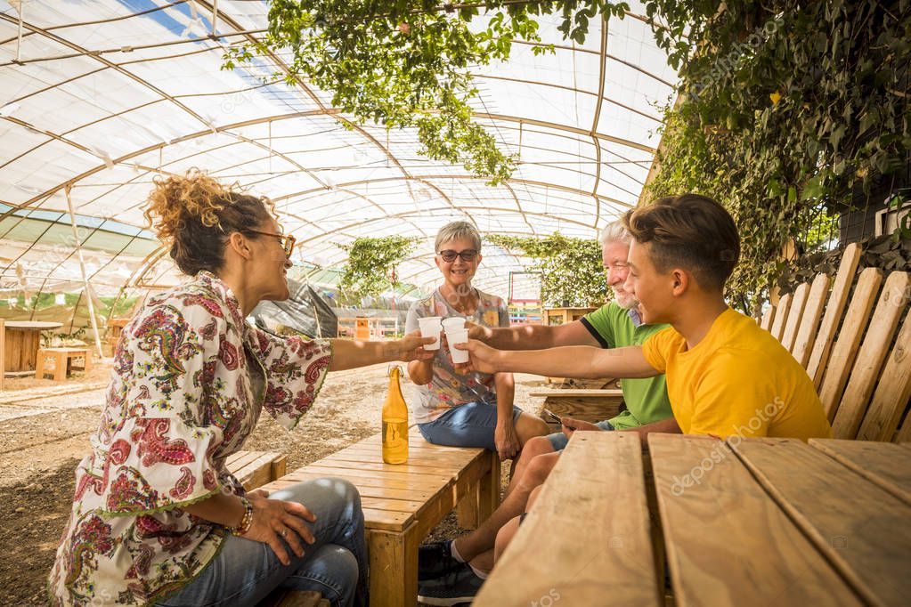family drinking and cheers together in outdoor leisure activity in a restaurant made by recycled wood and in respect with the nature. everybody smile and enjoy the easy lifestyle. from young to old ages