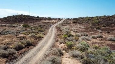 Kanarya Adaları'nda volkanik manzara üzerinde bisikletle seyahat eden kadın.