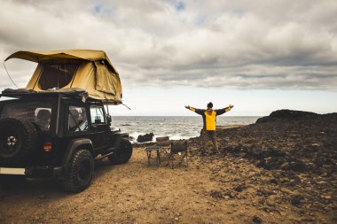 özgürlük ve explorer kavramı zevk için maceracı adam ile yolculuk seyahat yol araba ve çatı çadır kapalı. doğanın gücünü yaşayan dünya keşfetmek. okyanus kıyısında ev görmek. her yerde sürüş