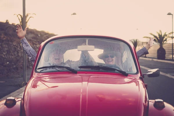 İki son sınıf erkek ve kadın için eski bir kırmızı araba, o gülümsüyor ve baktığını. Şapka ile her ikisi de. Alternatif seyahat kavramı.