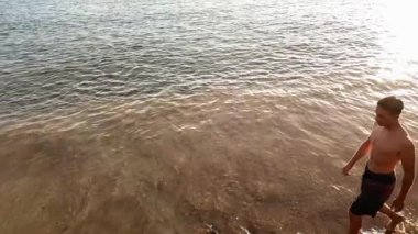 yakışıklı beyaz genç kızla sahilde yürüyüş ve arka planda Altın ışık günbatımı zevk 15 yaşında kaslara.