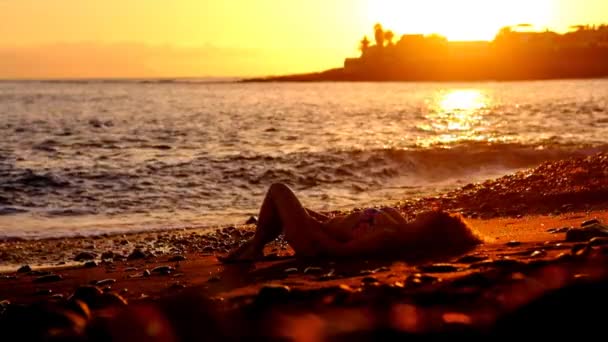 黄金の素晴らしい夕日の中に海の波の近くの砂の上リラックスした美しい白人女性を置きます モデルではビーチを楽しむ休暇とライフ スタイルの屋外活動の概念 — ストック動画