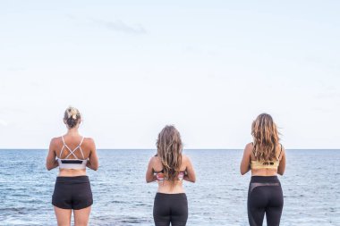Üç güzel kız görüntülenen arka taraftan yoga meditasyon fitness egzersiz okyanusun doğanın enerji almak ve bir özgürlük alternatif yaşam tarzı zevk için önünde için. açık eğlence spor etkinlik kavramı