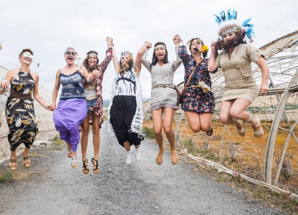 party on with many beautiful females mixed ages from young to middle to old ones everybody jump with joy. hippy and alternative dresses and summer festival concept outside in the countryside
