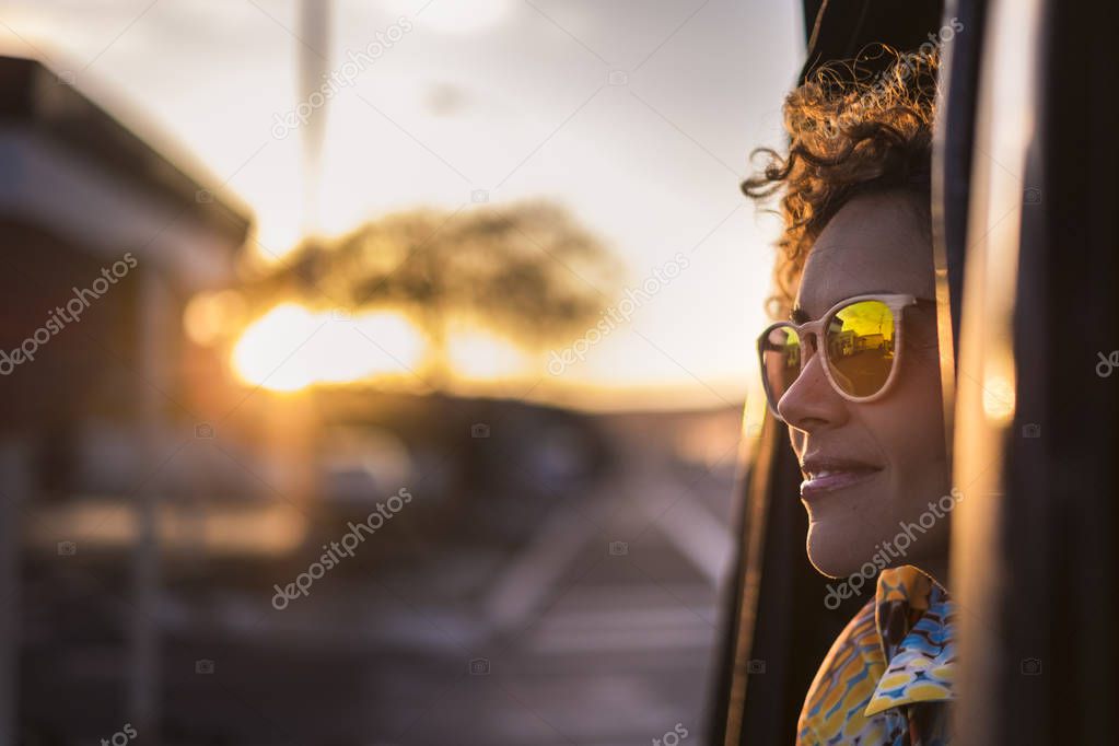 beautiful woman travel on a car looking outside and enjoy the light of the golden sunset on her face. nice lifestyle and peaceful emotions traveling around the world
