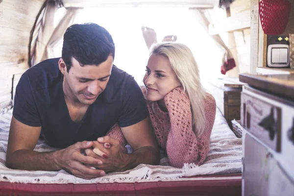 caucasian couple in love and romantic scene inside an old vintage camper ready to travel and have a vacation together with happiness and joy. blonde beautiful model lay down and stay nice