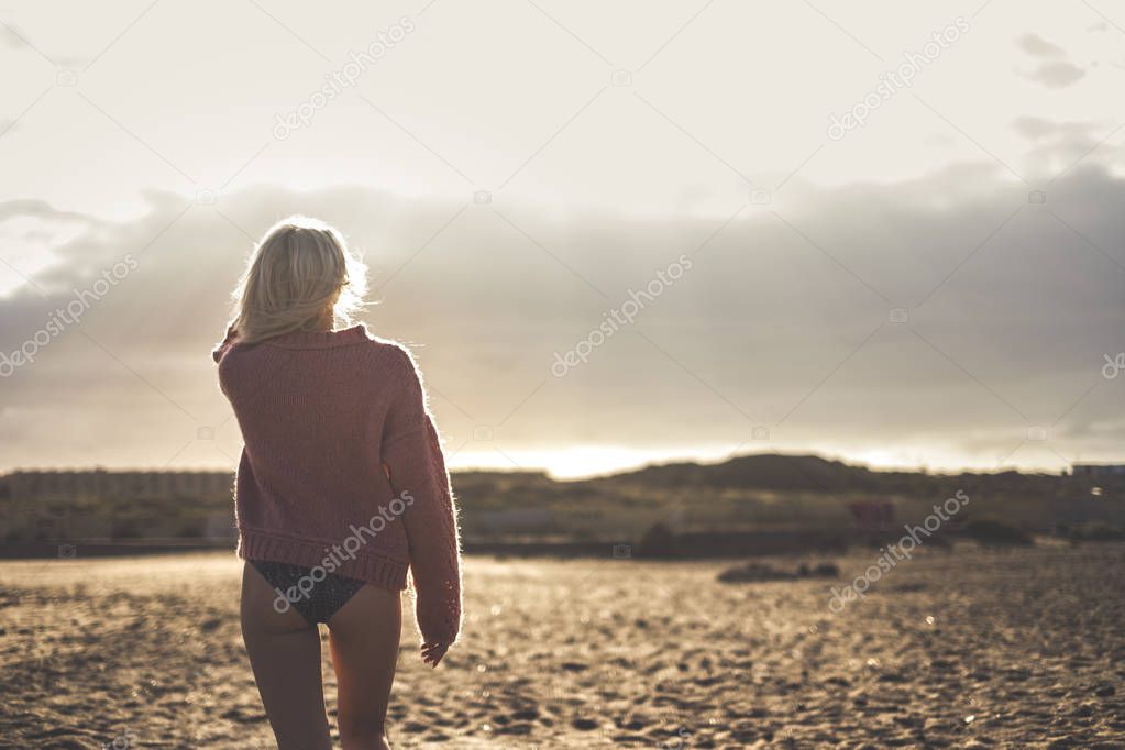 beautiful body and sexy blonde model walking away and viewed from back side. sunset time and outdoor beach leisure activity for vacation and travel alone concept