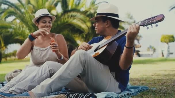 Mulher Soprando Bolhas Sabão Enquanto Homem Tocando Guitarra Parque — Vídeo de Stock