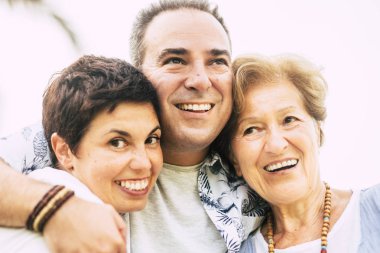 Modern aile bireyleri için mutluluk ve neşe dolu yakın plan portre anne, oğul ve kız arkadaşlar hepsi bir araya toplanmış gülümsüyor ve beyaz bir geçmişle eğleniyorlardı.