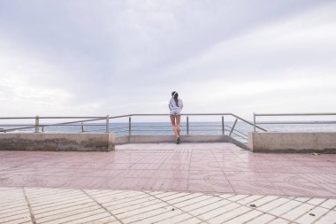 arka teras üzerinde duran genç kadın görünümünü ise okyanus arka planda müzik dinleme