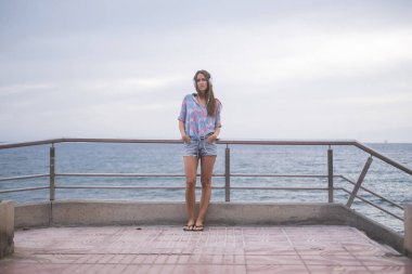 terasta duran genç kadın ise okyanus arka planda müzik dinleme