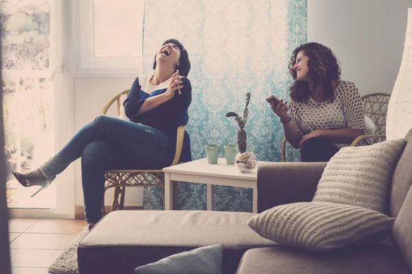 Mujeres Alegres Sentadas Sillas Casa Riendo Mientras Usan Teléfonos Inteligentes — Foto de Stock