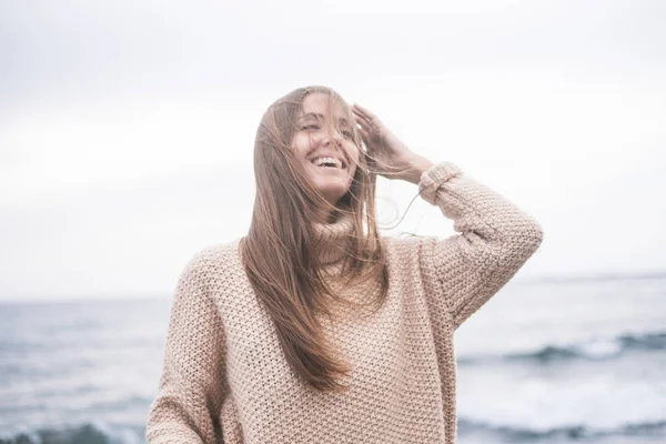 portrait of young woman in sweater posing on ocean background