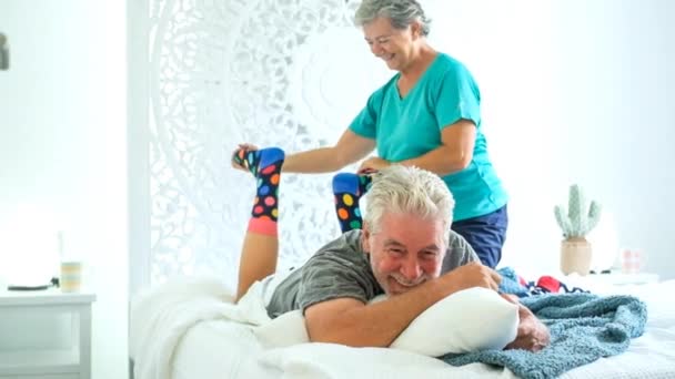 シニアのカップルが自宅のベッドに横たわっている間楽しい時を過す — ストック動画