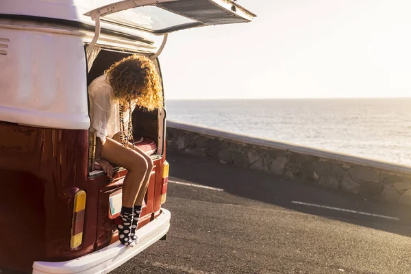 Yolculuk tutkusu konsepti vintage bir minibüsten oturan genç kafkas kadın seyahat ile 