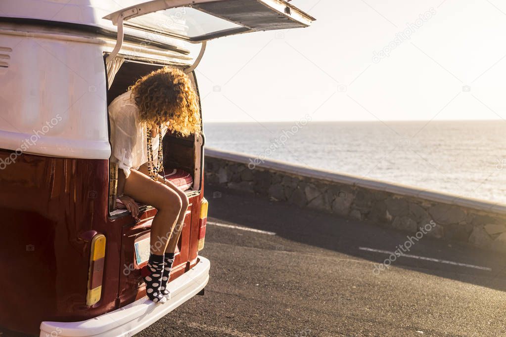 wanderlust concept with young Caucasian woman traveler sitting out of a vintage van 