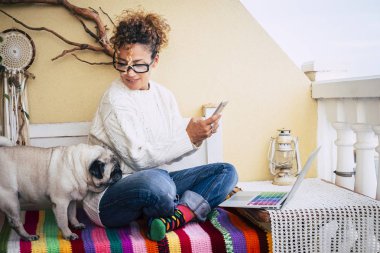 Dizüstü bilgisayarda çalışırken onun köpek pug ile oturan beyaz genç kadın