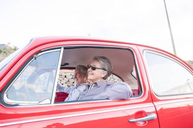 Tatil sırasında eski model kırmızı araba sürüş Kıdemli yaşlı çift 