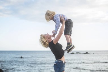 Anne ve oğul sarılıp oynuyorlar tatil aktivitelerinde gün batımında ve bulutlarda arka planda. Mutlu insanlar için yaşam tarzı