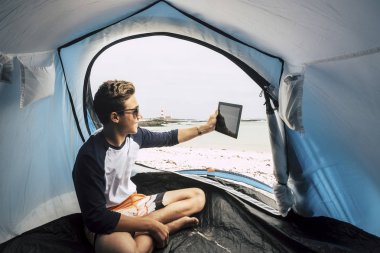 delikanlı adam beyaz plaj ve tablet PC'de alarak resim kamp