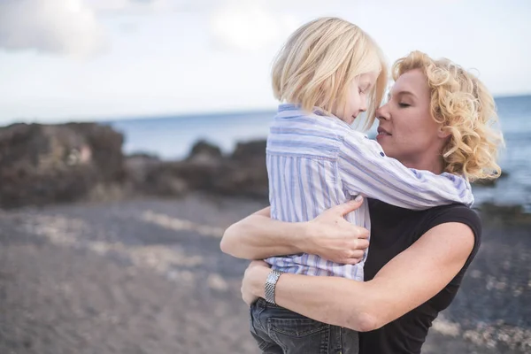 年轻美丽的金发母亲亲吻她的儿子 同时用爱心和感情拥抱他 — 图库照片