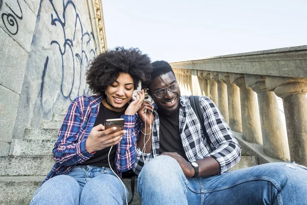 young couple enjoying music and holding modern smartphone