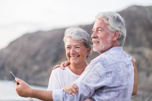 Glückliches Senioren Paar Mit Handy Kieselstrand Lacht Und Scherzt — Stockfoto