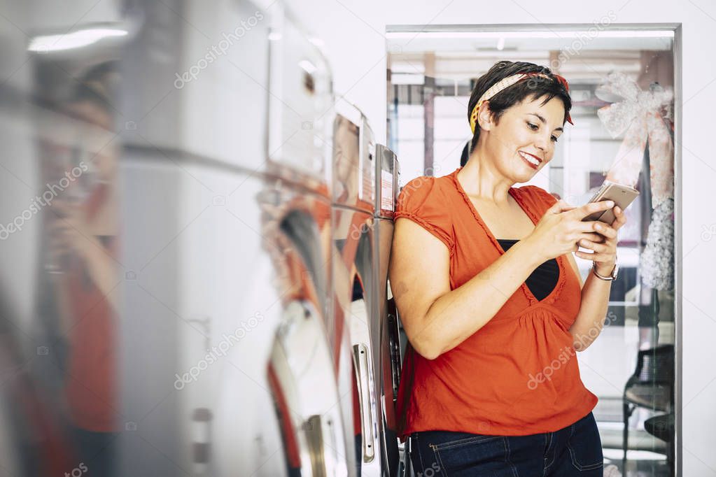 Woman using smartphone at laundry mat automatic service shop