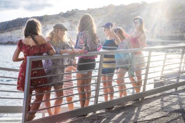 eğleniyor ve okyanusu günbatımı arka plan üzerinde yakın açık gülüyor kadın grubu