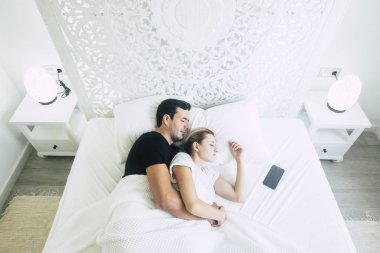 evde yatakta uyuyan genç çiftin havadan görünümü