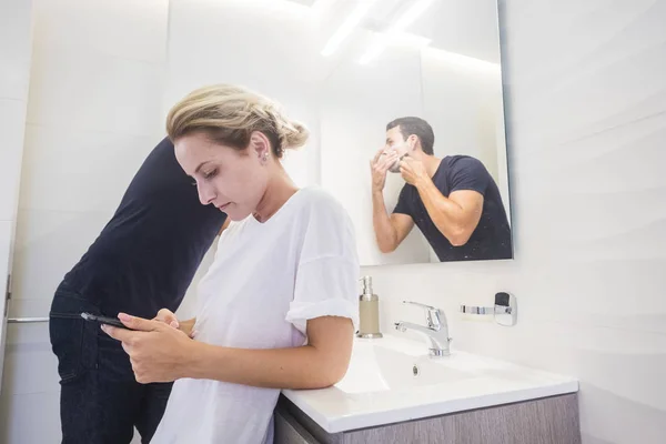 Jovem Loira Olhando Para Smartphone Enquanto Homem Fazendo Barba Com — Fotografia de Stock