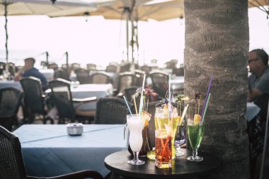 Karışık kokteyller bir açık hava bar restoranında, insanlar oturmadan ve almadan gösterildi ve ifşa edildi. Barmenin müşteriler için yapabileceklerinin renkleri ve örnekleri.