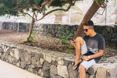 Genç, modern, yakışıklı, milenyum çocuğu akıllı telefonundaki içerik ve mesajları okuyup yazıyor.