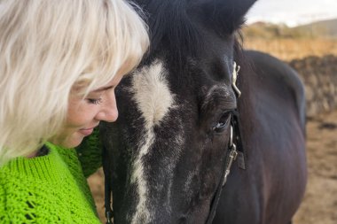 Sarışınla yüz yüze güzel manken ve inanılmaz güçlü siyah at dostluk ve sevgi içinde bir arada kalın.