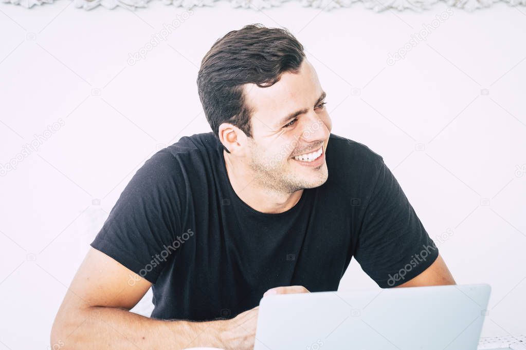 Young handsome millennial cheerful boy smile and laugh while work with a laptop 