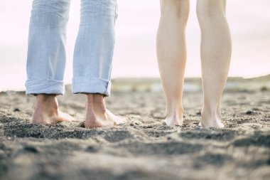 feet of man and woman standing on sand at beach  clipart