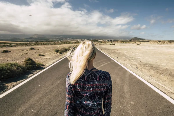 在乡间一条笔直的长路上 一个年轻的金发姑娘从后面的人行道上眺望着 — 图库照片