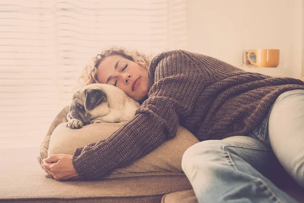 Caucasian lady sleeping at home and hugging her best lovely friend pug on sofa