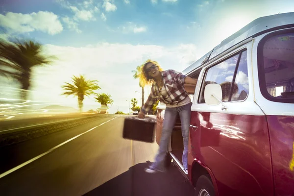 woman jumping outside of red vintage van while traveling at daytime