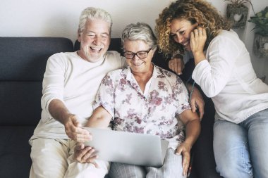 İç mekandaki insanlar evlerinde dizüstü bilgisayar kullanarak ve arkadaşlarıyla ya da aileleriyle arkadaşça sohbet ederek eğleniyorlar. 