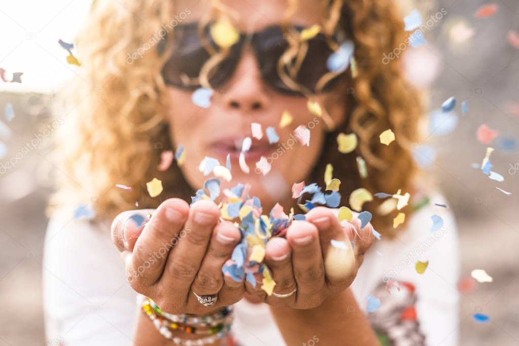 Close up of woman blowing out colored carnival party confetti 