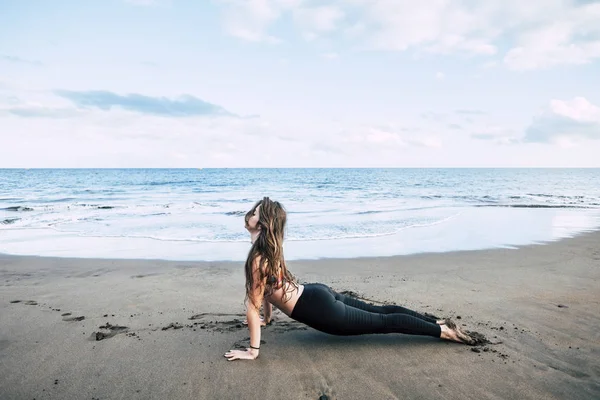girl having balance pilates workout exercise at beach