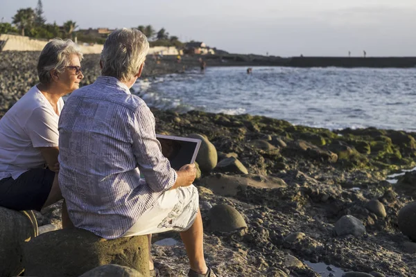 Pareja Ancianos Con Tablet Playa Guijarros Con Fondo Azul Mar —  Fotos de Stock