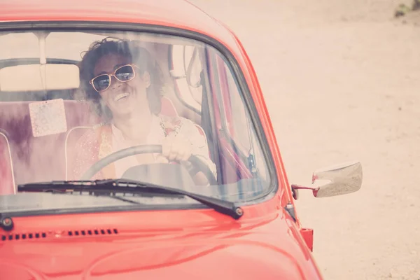 middle age lady driver posing inside of red legendary retro vintage car
