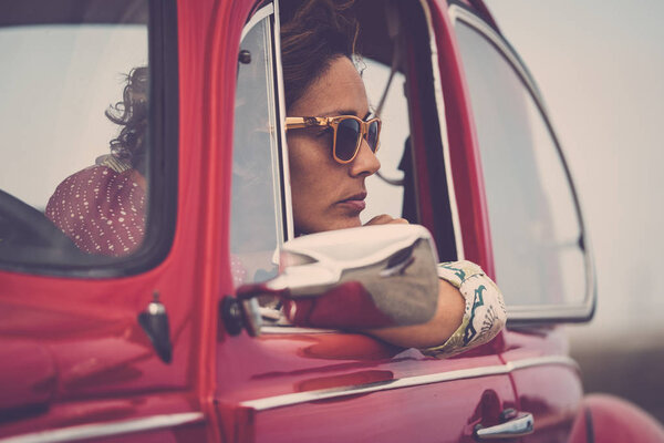 middle age lady driver posing inside of red legendary retro vintage car
