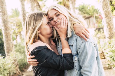 Komik sarışın kızlar sarılıyor ve yüzleri olan çılgın bir ifade takınıyorlar.