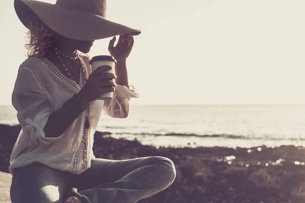 旅游和人们的概念 戴着太阳帽和一杯咖啡的面带微笑的女人 或在有地平线和大海的海滩边喝背景水的女人 时尚的户外风尚和嬉皮士风格 — 图库照片